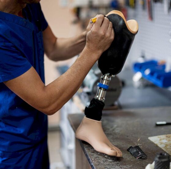 Technik ortopeda pracuje przy protezie nogi w pracowni protetycznej