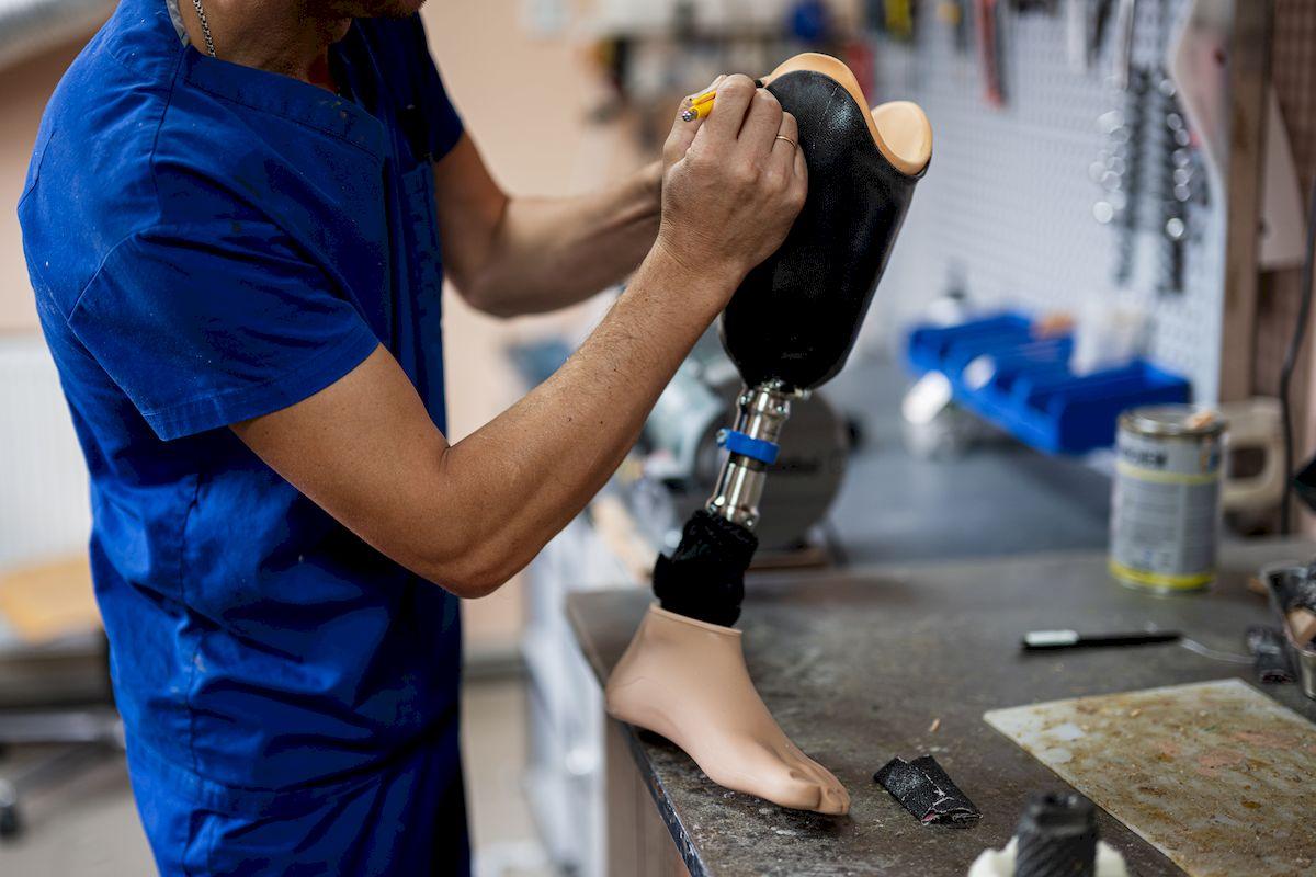 Technik ortopeda pracuje przy protezie nogi w pracowni protetycznej
